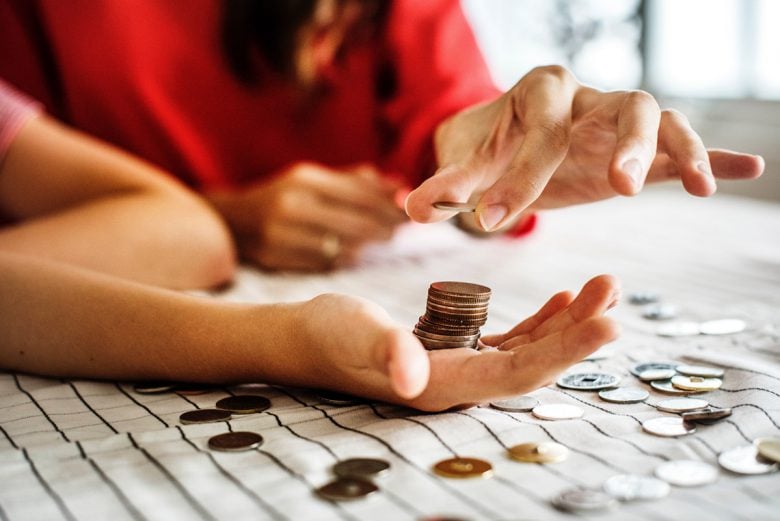 Two people counting change to create more money and happiness