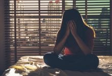 Girl sitting on bed holding her head in her hands - how to calm an overactive mind