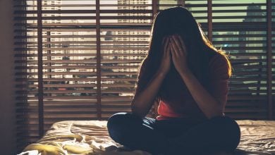 Girl sitting on bed holding her head in her hands - how to calm an overactive mind