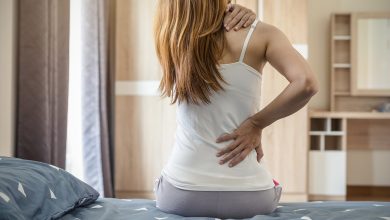 Woman sitting up in bed with neck and back pain