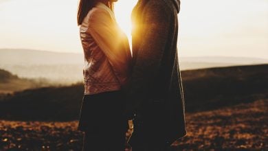 Woman and man holding hands in front of the sunset