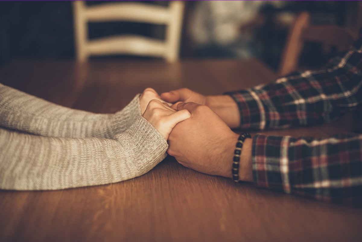 Couple holding hands across the table, creating connection