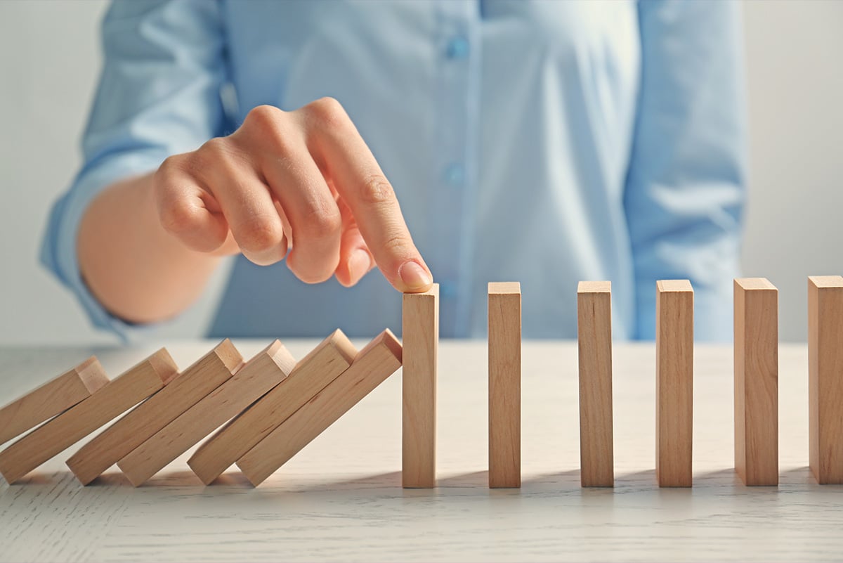 Woman stopping dominoes from falling further