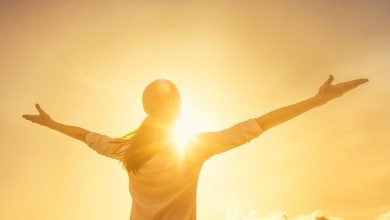 Woman with arms wide, facing the sun