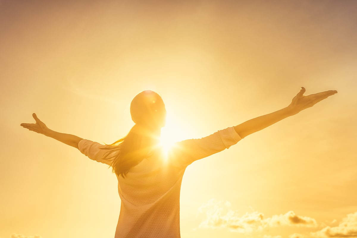 Woman with arms wide, facing the sun