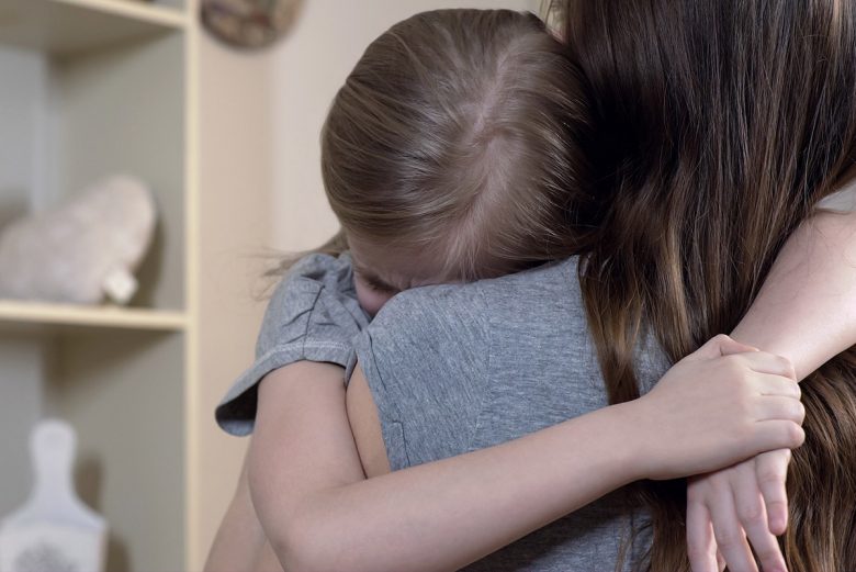 Child crying on mother's shoulder