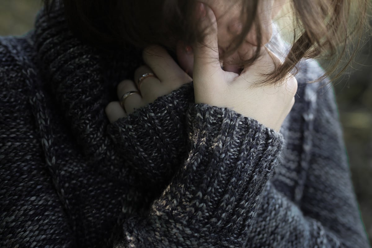Woman sad with arms crossed by face