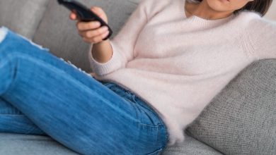 Woman sitting on couch holding remote