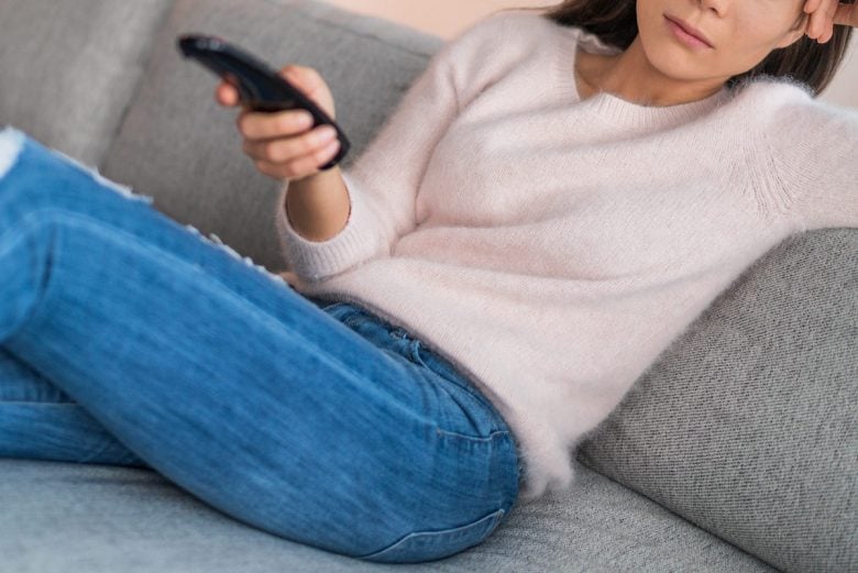 Woman sitting on couch holding remote