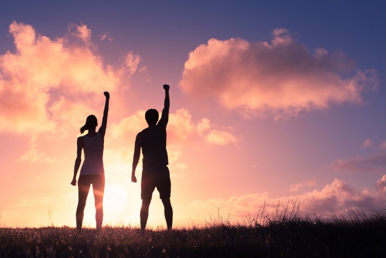 Woman and man standing strong - silhouette in front of sunset