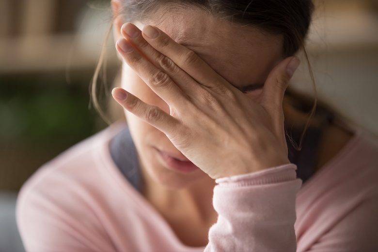 Stressed woman covering her face with one hand