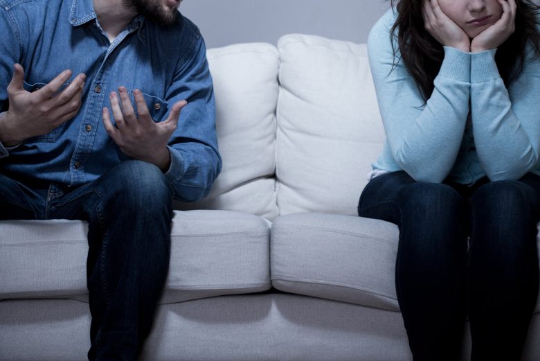 Man and woman sitting on a couch arguing