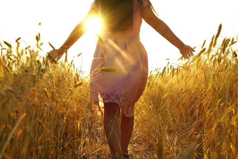 Woman walking through fields into the sunset- how to finally heal a lifelong pattern