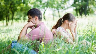 Man and woman sitting back to back in field of grass