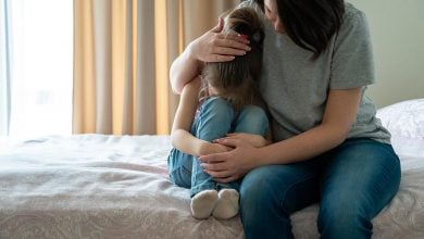 Mother comforting child on bed - how to protect your child from negative energy