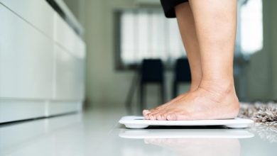 Woman standing on scale in her home