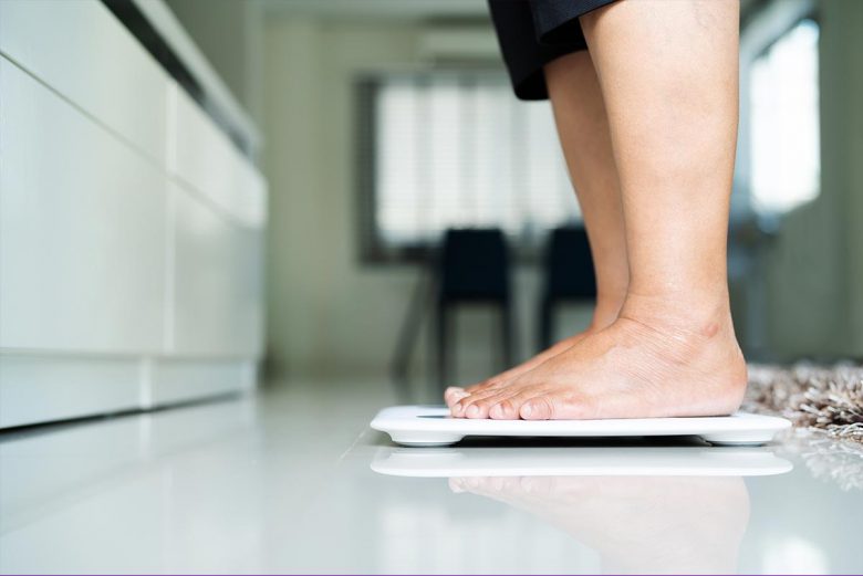 Woman standing on scale in her home