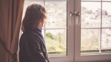 Woman with wavy hair looking out a window on a quaint city