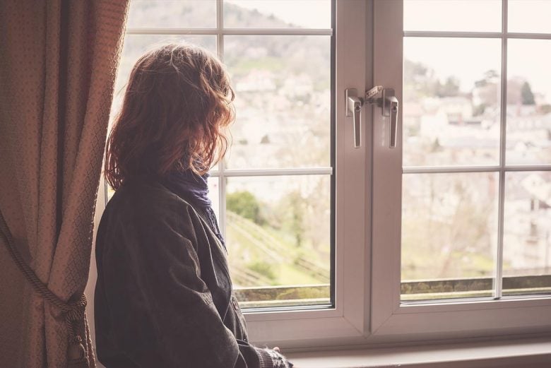 Woman with wavy hair looking out a window on a quaint city
