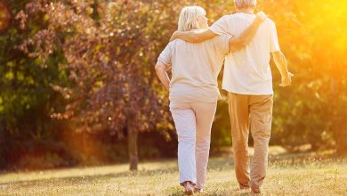 Man and woman walking with arms around each other during golden hour
