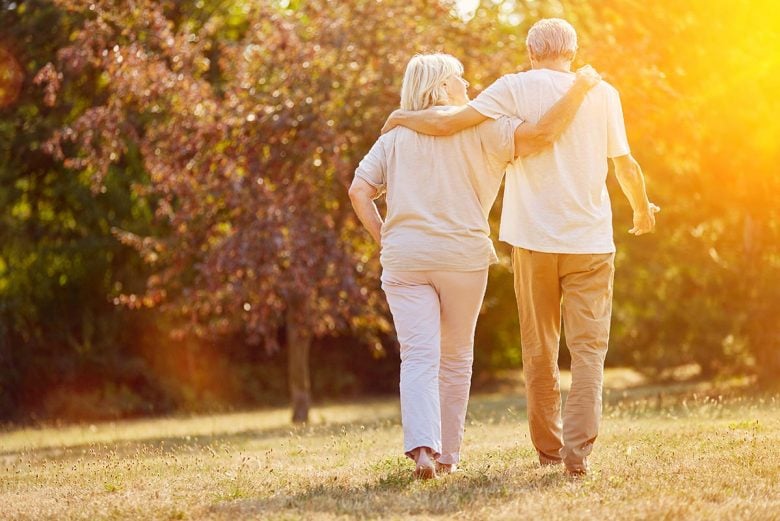 Man and woman walking with arms around each other during golden hour