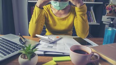 Woman at desk with mask on, stressed out
