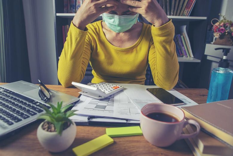 Woman at desk with mask on, stressed out