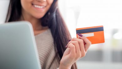Woman smiling at laptop holding credit card