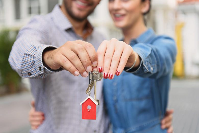 Couple holding a key to their new home - how to beat the housing market and find a home you love
