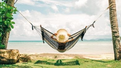 Woman relaxing in hammock by the ocean
