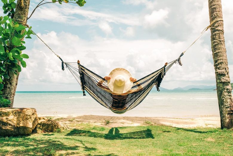 Woman relaxing in hammock by the ocean