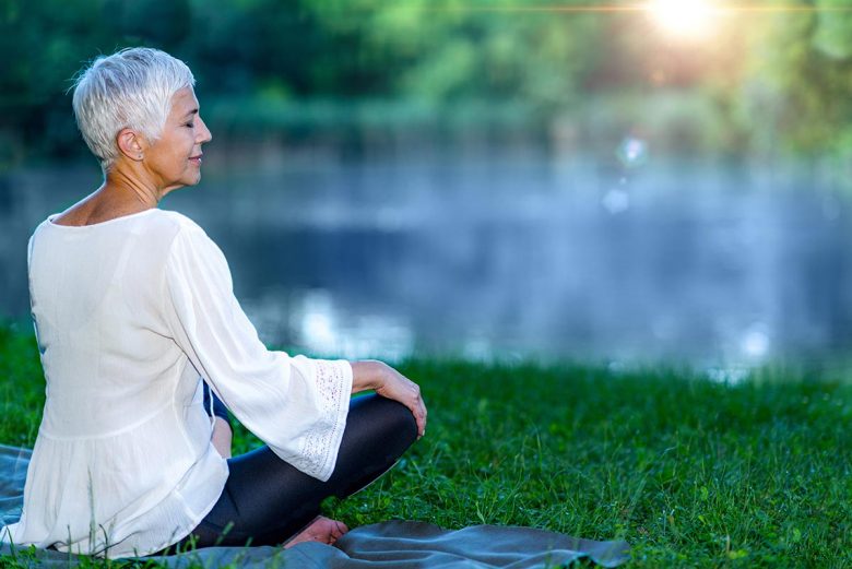 Older woman sitting by lake