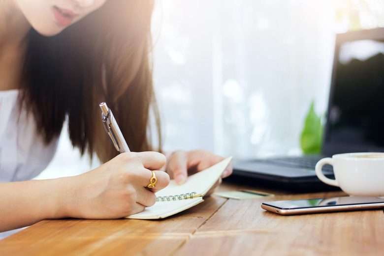 Asian woman journaling with the Healing Center