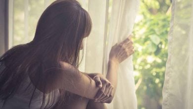 Woman looking out the window with social anxiety