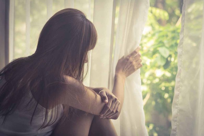 Woman looking out the window with social anxiety