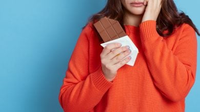 Woman eating chocolate bar looking sad